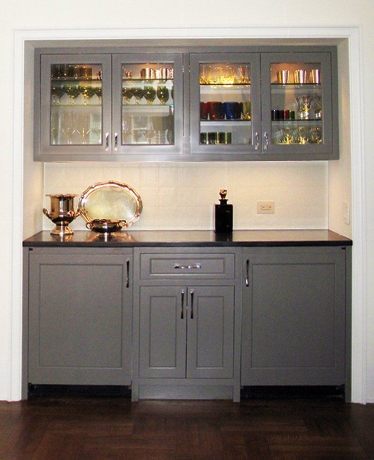 A kitchen with gray cabinets and black counter tops