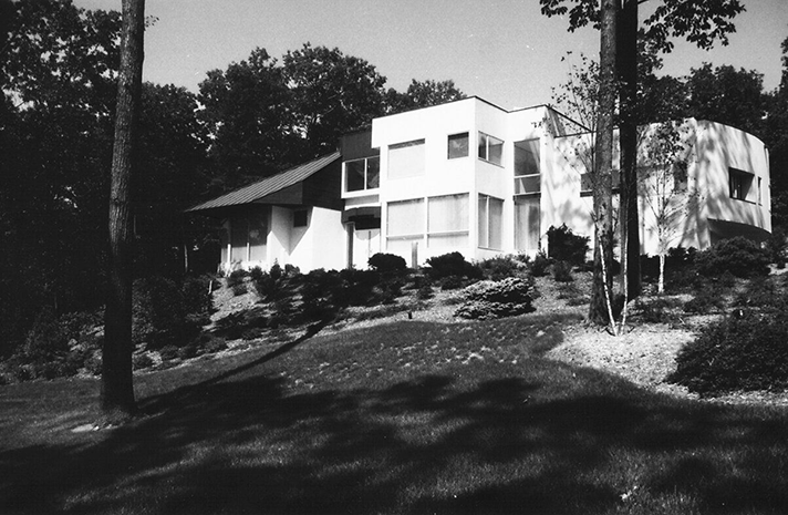 A black and white photo of a house surrounded by trees