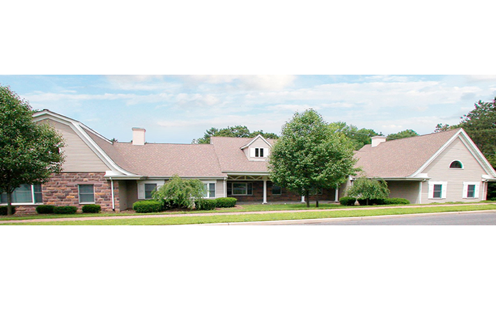 A large house with a brown roof is surrounded by trees