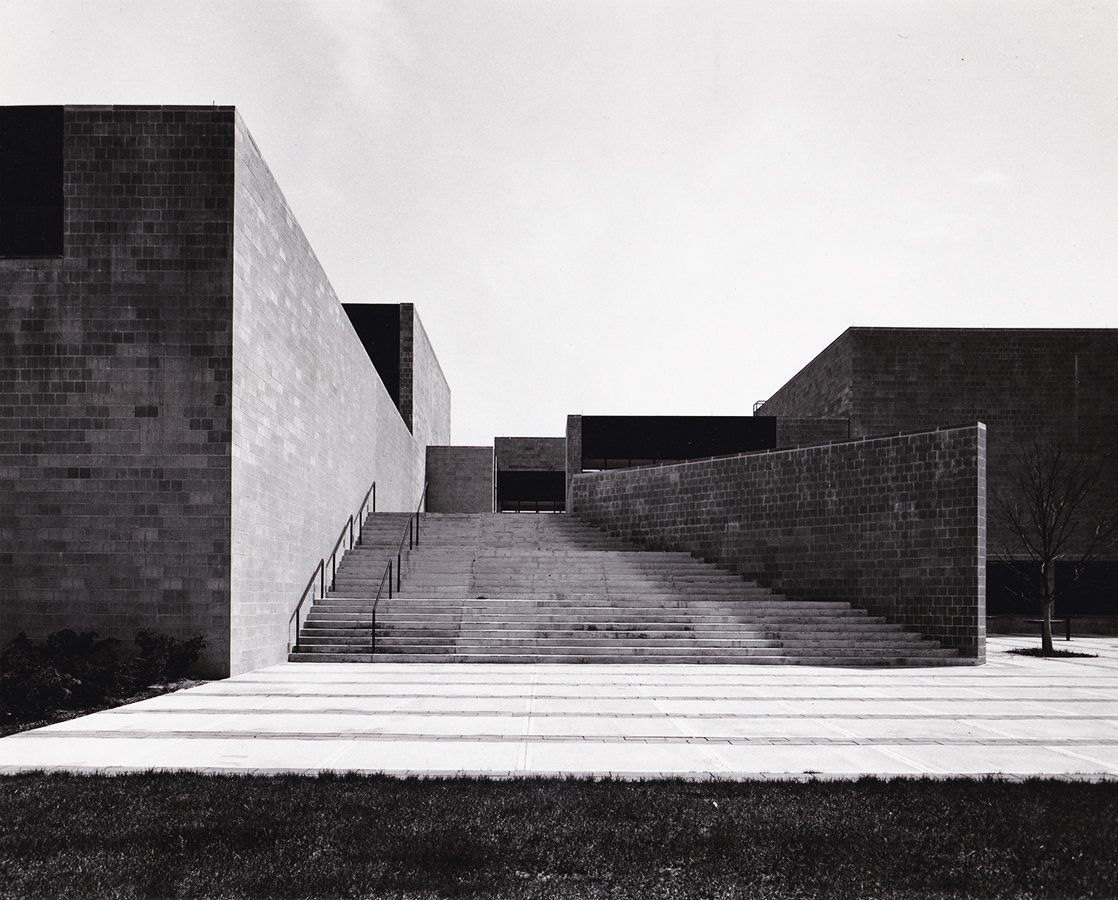 A black and white photo of a building with stairs leading up to it.