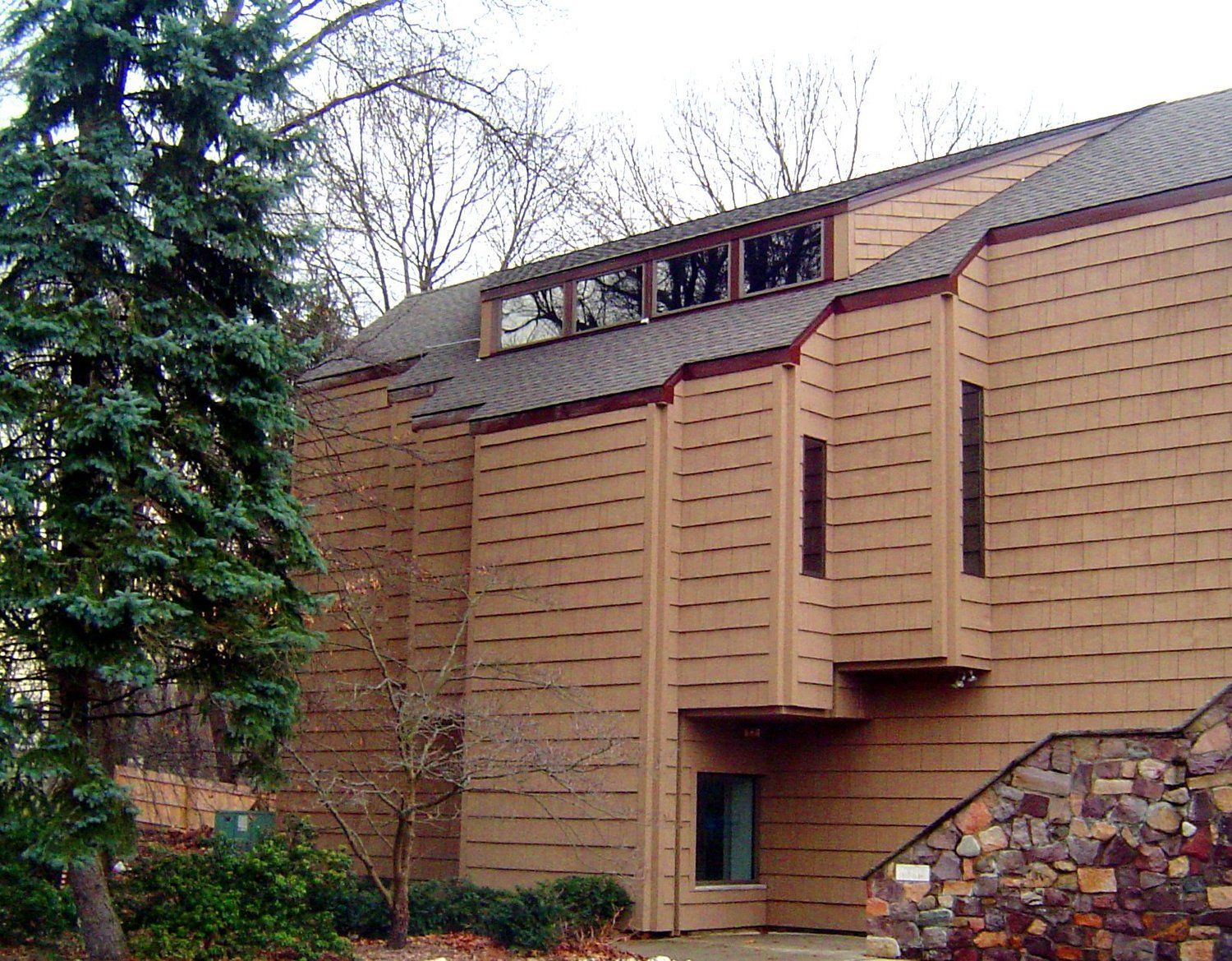 A large brown house with a stone wall and stairs