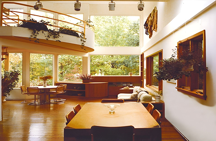 A dining room with a table and chairs and lots of windows