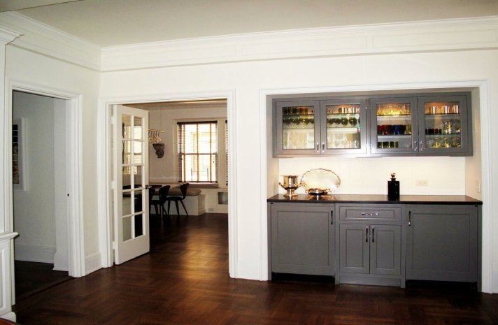 A kitchen with gray cabinets and black counter tops