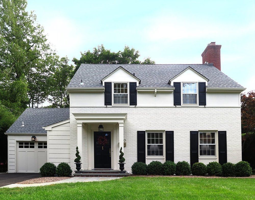 A white house with black shutters and a garage