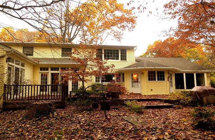 The backyard of a house with leaves on the ground