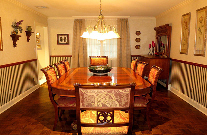 A dining room with a large wooden table and chairs