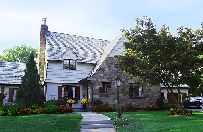 A white house with a stone facade and a gray roof