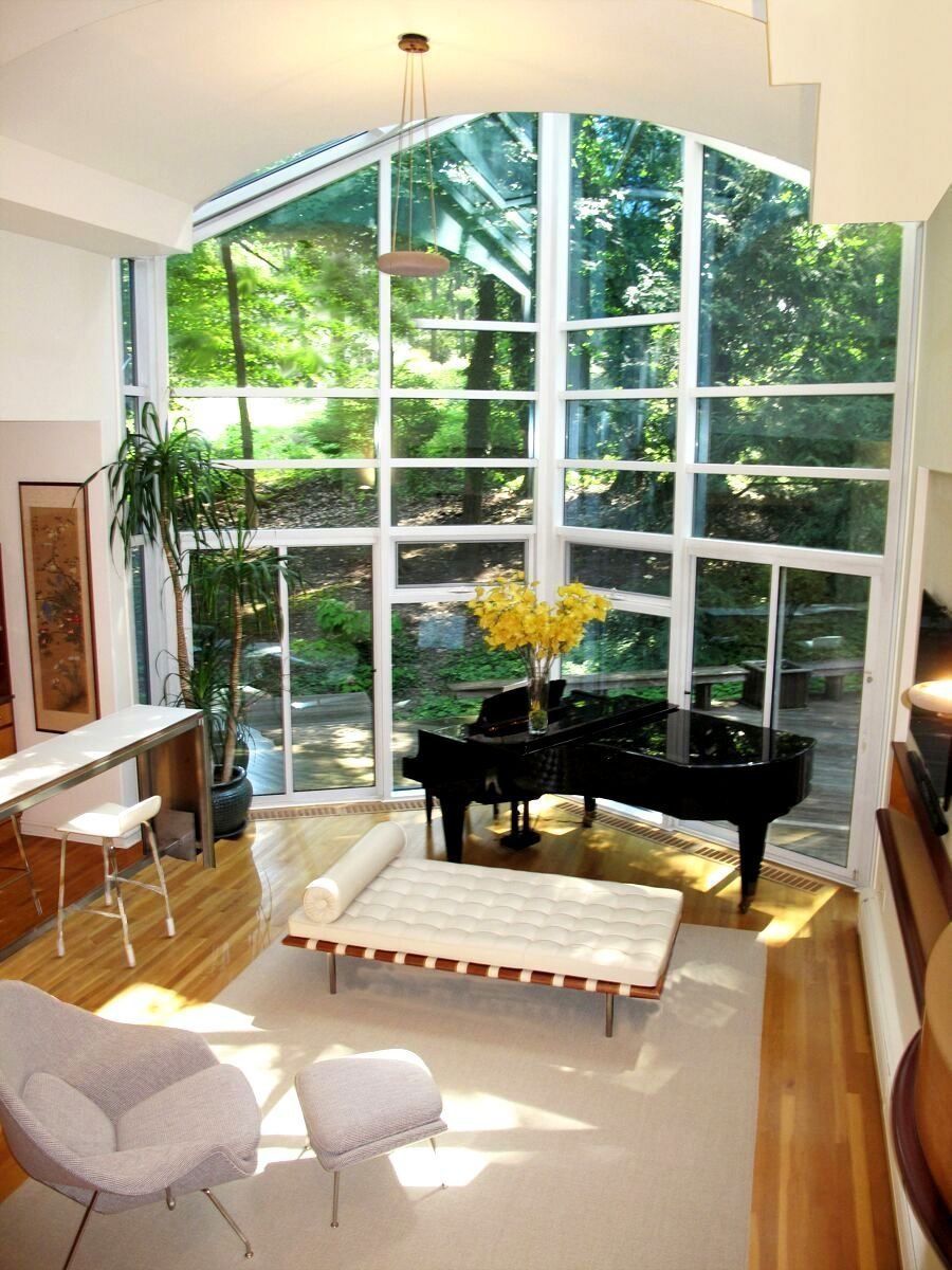 A living room with a piano and lots of windows