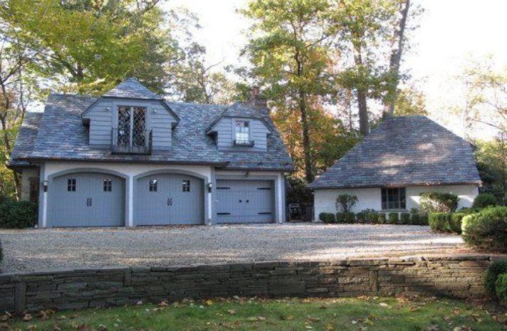 A house with three garage doors and a thatched roof