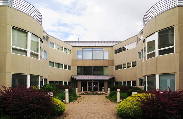 A large building with a lot of windows and bushes in front of it