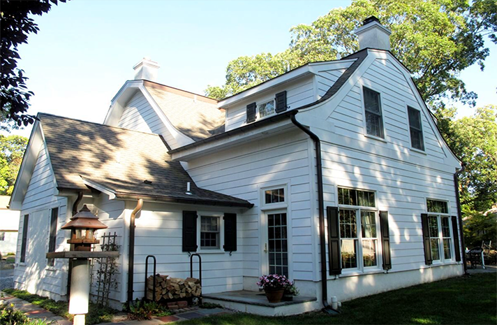 A white house with black shutters and a chimney