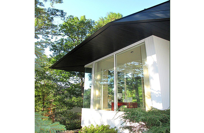 A white house with a black roof and lots of windows