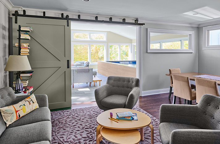 A living room with a sliding barn door between the living room and dining room.