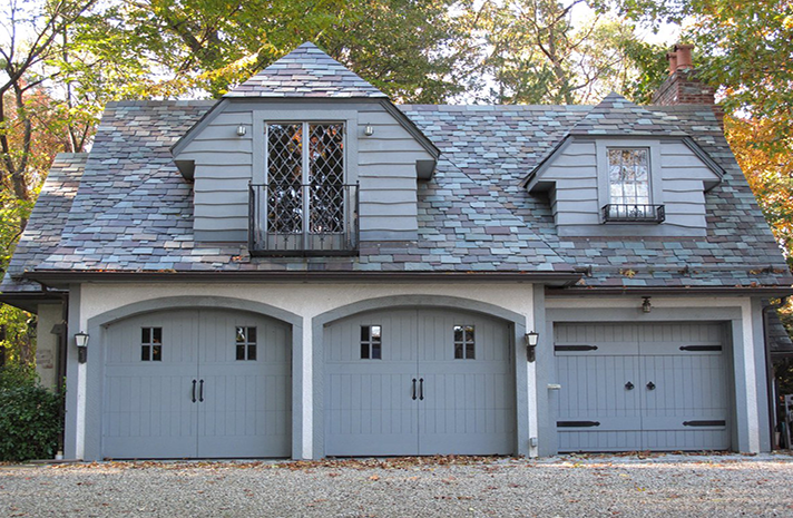 A garage with three doors and a slate roof