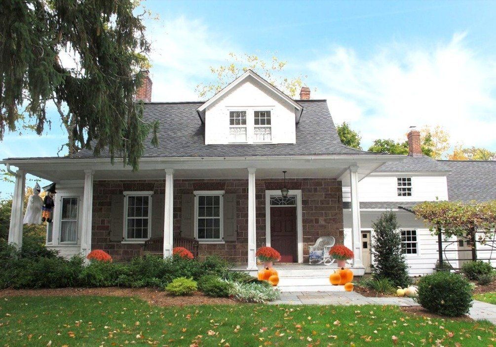 A large brick house with a porch and pumpkins in front of it