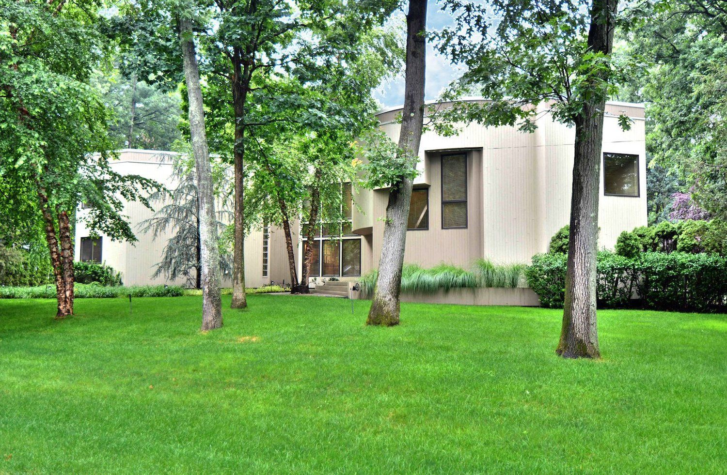 A house with a lush green lawn and trees in front of it