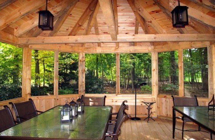 A screened in porch with a table and chairs and lanterns