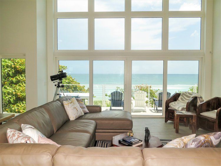 A living room with a couch and chairs and a view of the ocean.