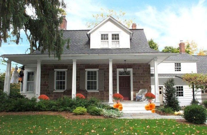 A large house with a porch and pumpkins on it