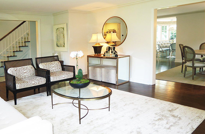 A living room with a couch , chairs , a coffee table and a mirror.