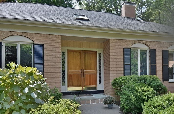 A brick house with black shutters and a skylight on the roof