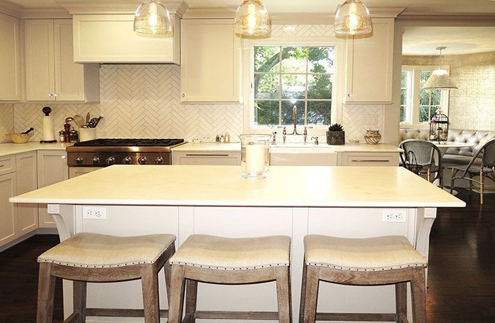 A kitchen with a large island and three stools.
