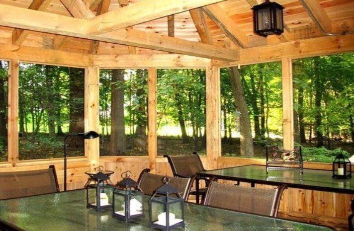 A screened in porch with tables and chairs and a ceiling fan