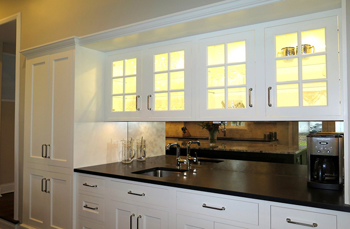 A kitchen with white cabinets and black counter tops