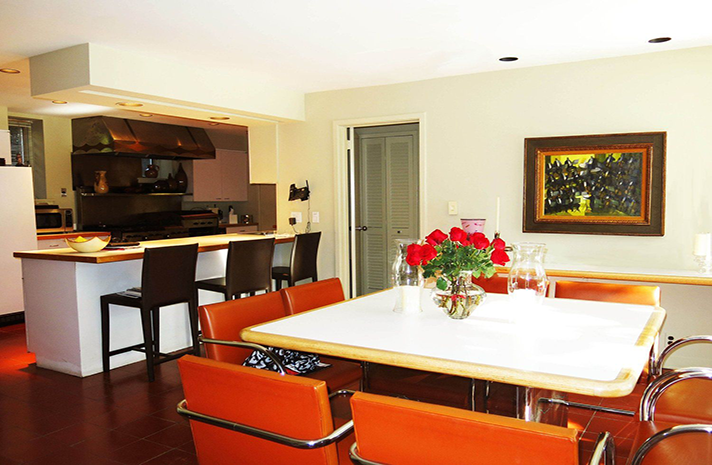 A dining room with a table and chairs and a painting on the wall