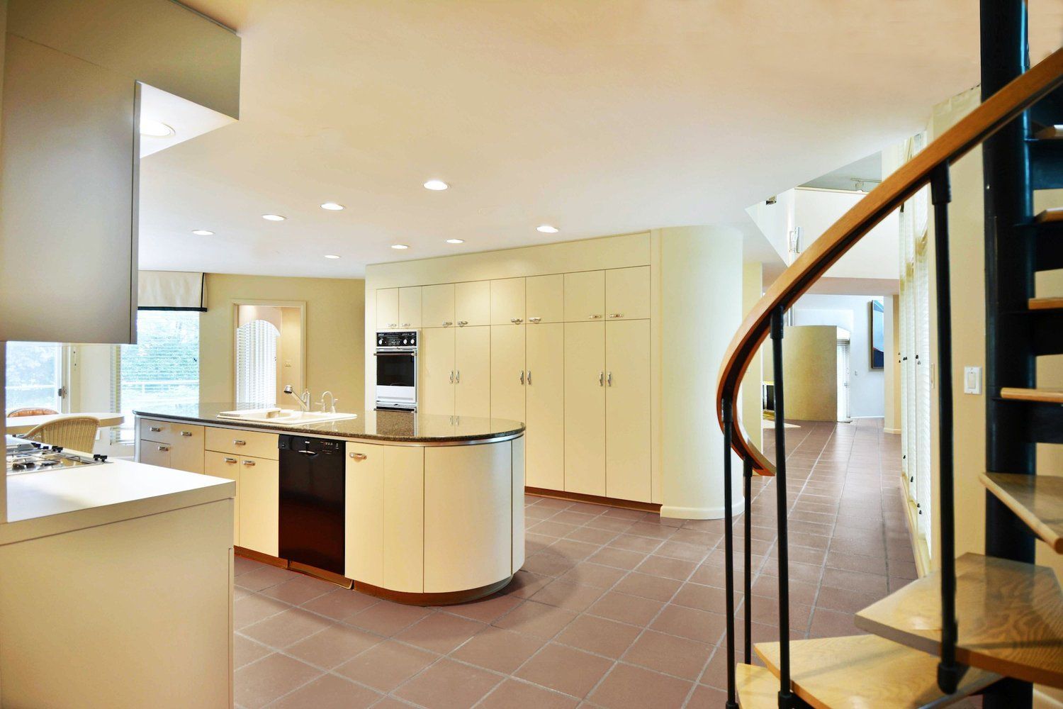A kitchen with a spiral staircase leading to the second floor