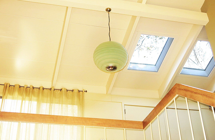 A ceiling with two skylights and a light hanging from it