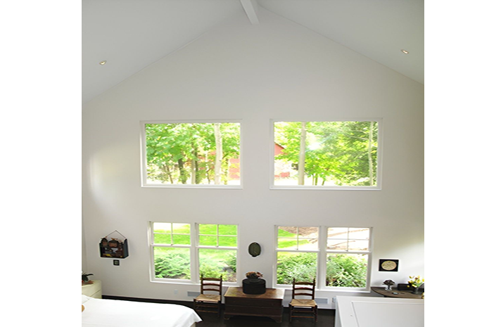 A bedroom with a vaulted ceiling and lots of windows