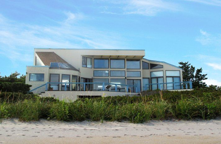 A large house sits on top of a sandy hill