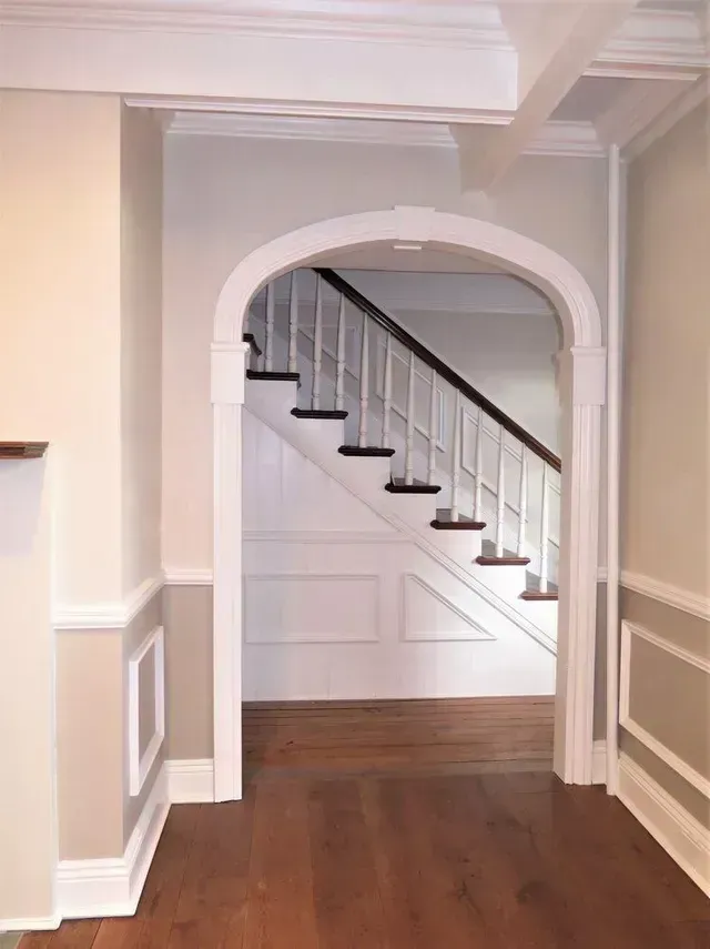 A hallway leading to a staircase with a wooden railing