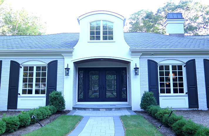 The front of a white house with black shutters