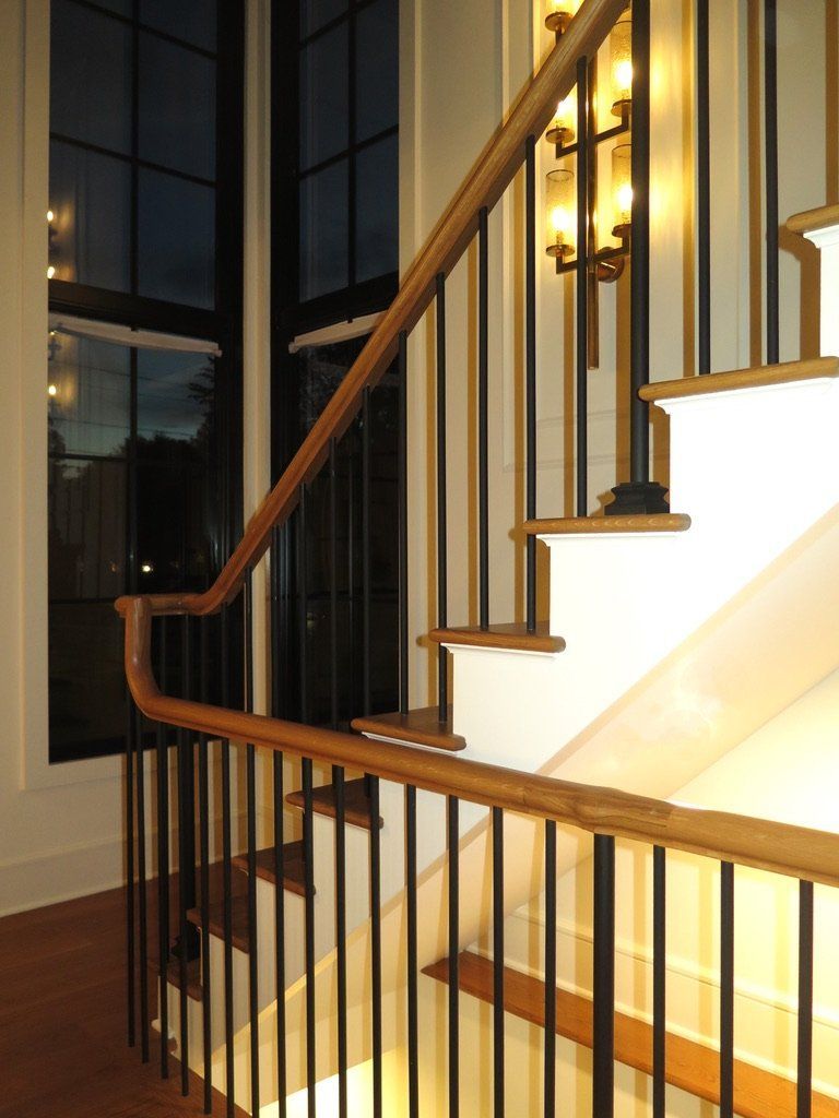 A staircase with a wooden handrail and a black railing