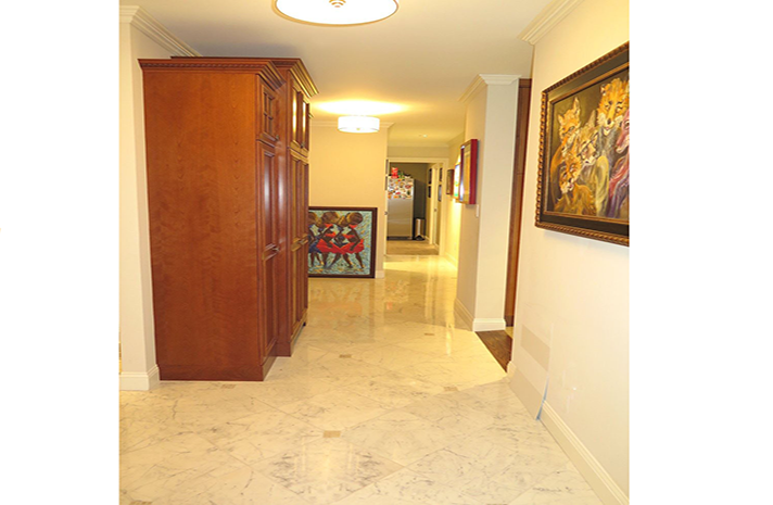 A hallway with a wooden cabinet and a painting on the wall.