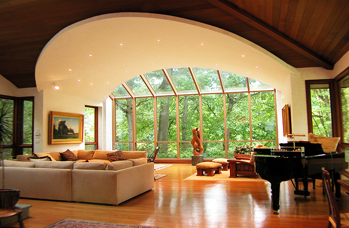 A living room with a piano and lots of windows