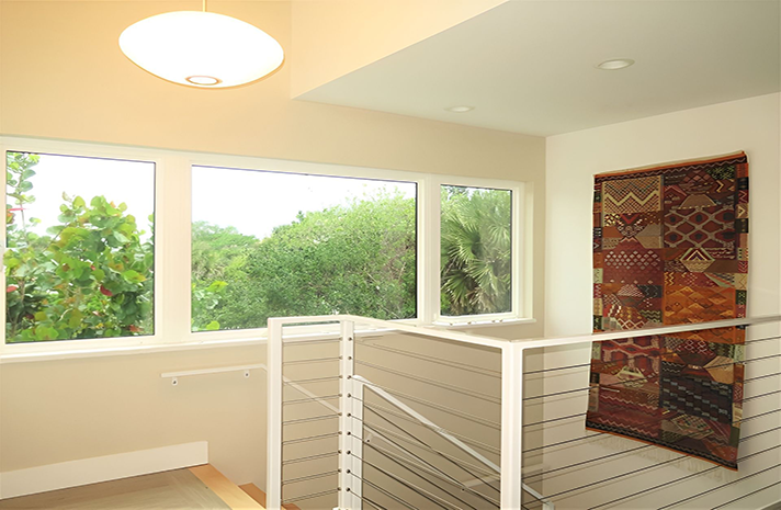 A staircase with a stainless steel railing and a large window