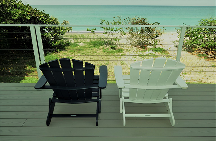 Two chairs on a deck with a view of the ocean