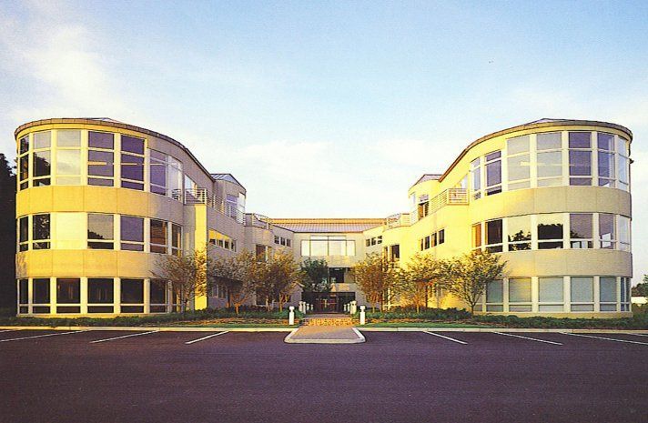 A large building with a lot of windows has a parking lot in front of it