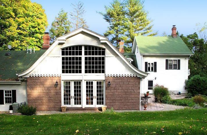 A white house with a green roof is next to a brick house