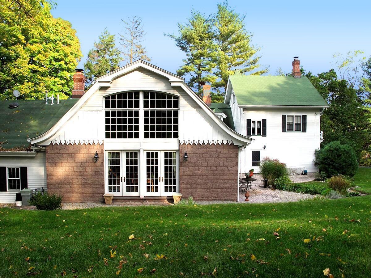 A white house with a green roof is next to a brick house