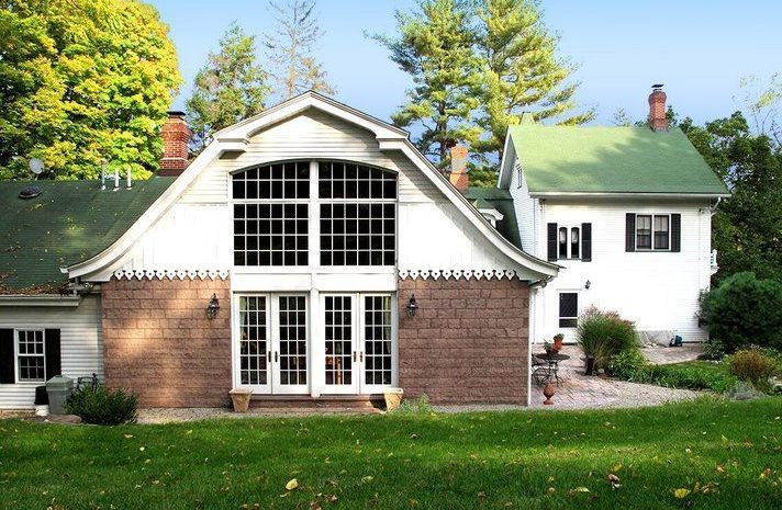 A white house with a green roof is next to a brick house