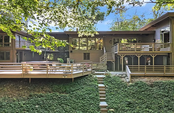 A large house with a large deck and stairs leading to it.