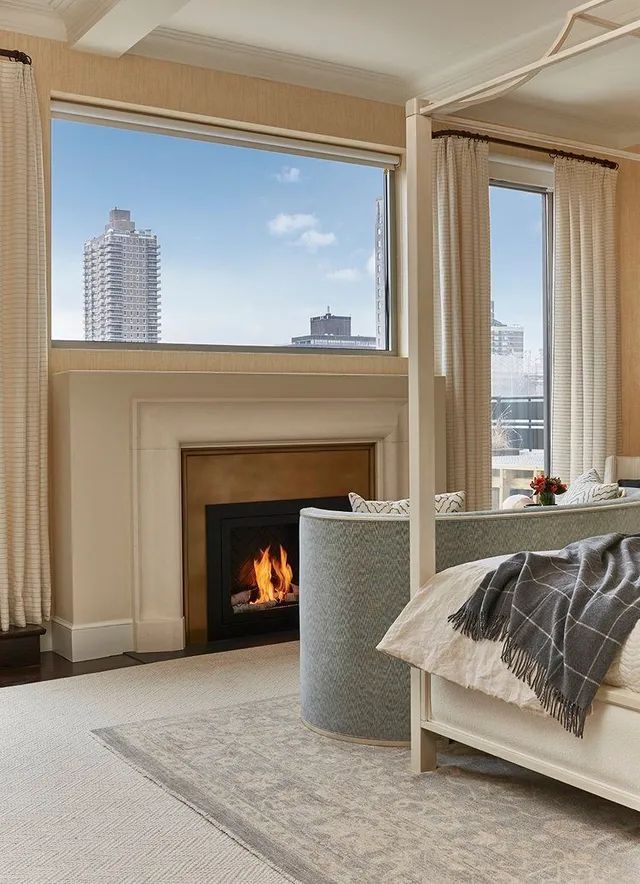 A bedroom with a canopy bed , fireplace , and large window.