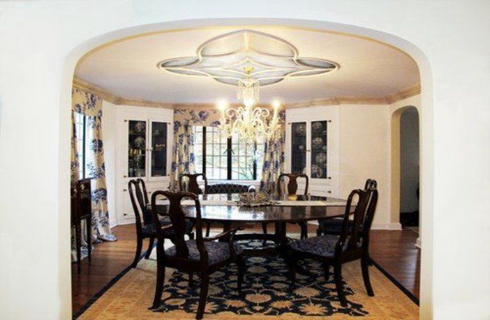 A dining room with a table and chairs and a chandelier hanging from the ceiling.