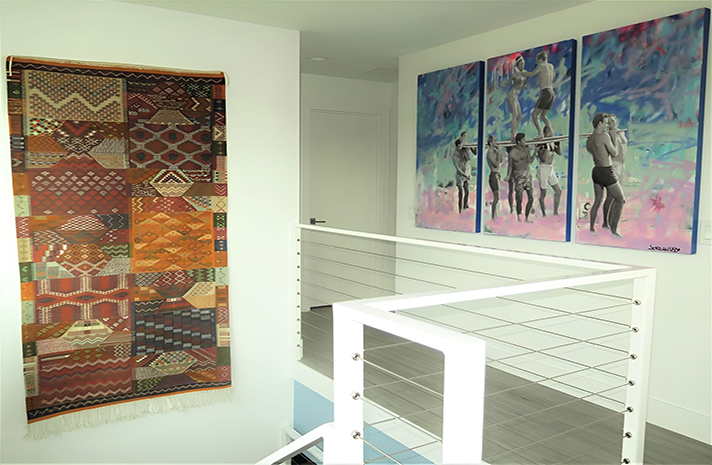 A staircase with paintings on the wall and a rug on the wall