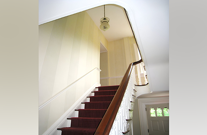 A staircase with a red carpet and white railing