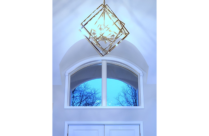 A chandelier is hanging from the ceiling above a window.